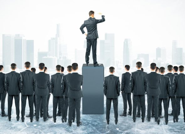 leadership-concept-with-businessman-standing-pedestal-looking-into-distance-with-other-businesspeople-around